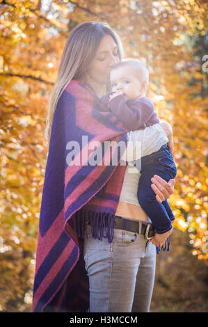 Madre nella foresta kissing Baby girl sul fronte Foto Stock