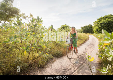 Giovane donna ciclismo su pista sterrata, Gili Meno, Lombok, Indonesia Foto Stock