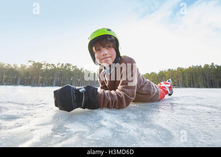 Ritratto di ragazzo disteso sulla sua parte anteriore sul lago ghiacciato, Gavle, Svezia Foto Stock