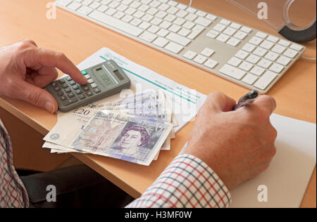 Primo piano di un uomo d'affari che compila il calcolatore del modulo di dichiarazione dei redditi per l'autovalutazione HMRC e Money England UK Regno Unito GB Gran Bretagna Foto Stock