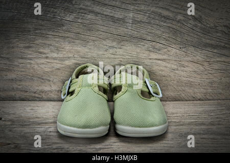 Scarpe di colore verde per il bambino su un vecchio scaffale di legno Foto Stock