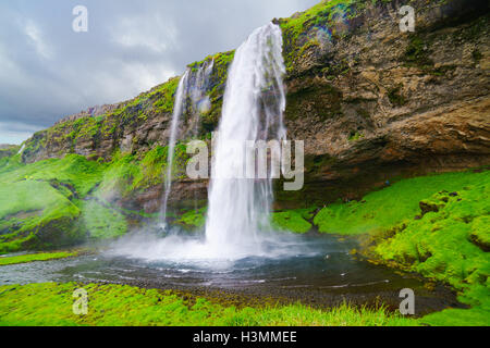 Seljalandsfoss in Islanda e le cascate che i visitatori possono camminare dietro di esso in una piccola grotta Foto Stock