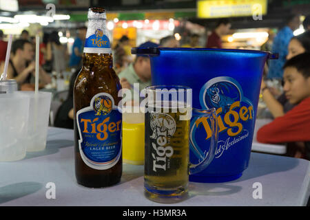 Una bottiglia di birra Tiger,vetro,& benna su una tabella all'interno di Jalan Alor Street,Kuala Lumpur, Malaysia, Foto Stock