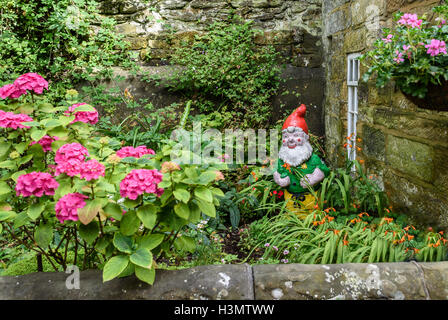 Gnomo da giardino in un giardino cottage. Foto Stock