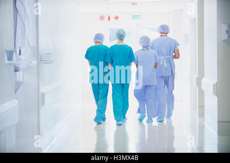 Vista posteriore di quattro il personale medico indossa scrubs camminando nel corridoio di ospedale Foto Stock