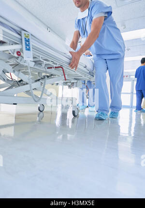 Due medici urgentemente spingendo letto di ospedale lungo il corridoio Foto Stock