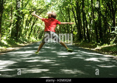 Vista posteriore del boy jumping a metà in aria Foto Stock