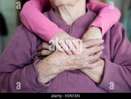 Irriconoscibile nipote tenendo le mani della nonna Foto Stock