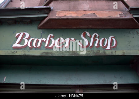 Antichi verde weathered Barber shop segno sulla pietra arenaria rossa edificio Foto Stock