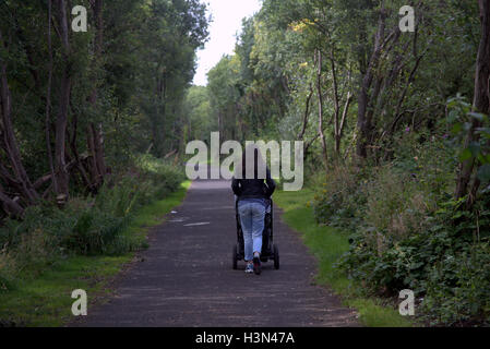 Glasgow park scene ragazza spingendo la PRAM in posizione di parcheggio Foto Stock