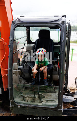 Un giovane ragazzo (4 anni) seduto a JCB (Escavatore) cabina fingendo di farlo funzionare. Foto Stock