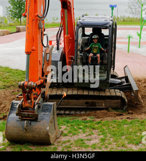 Un giovane ragazzo (4 anni) seduto a JCB (Escavatore) cabina fingendo di farlo funzionare. Foto Stock
