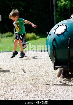 Un giovane ragazzo (4 anni) che salta da un parco giochi di installazione. Foto Stock