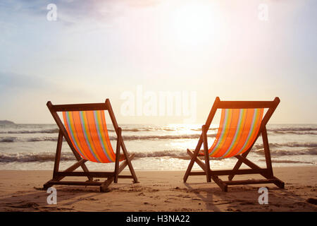 Due sedie a sdraio sulla spiaggia con sole luminoso e onde Foto Stock