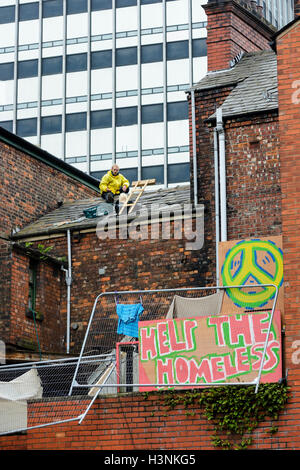 Manchester, Regno Unito. 11 ottobre, 2016. Un giovane uomo, Chris da Salford, sono saliti sul tetto del Ducie Bridge public house in Miller Street a 8-o-Orologio questa mattina in protesta per lo sfratto di 30 persone senzatetto che sono state squatting in costruzione per diverse settimane. Alta Corte i funzionari di polizia ha guadagnato l'entrata al palazzo di proprietà della società cooperativa, questa mattina di sfrattare la squatter che erano sfidando un alta corte ordine di sfratto. Credito: Dave Ellison/Alamy Live News Foto Stock