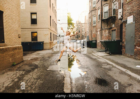 Donna saltando pozzanghera sulla strada, Boston, MA, Stati Uniti d'America Foto Stock
