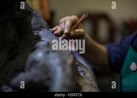 Vista ritagliata dello scultore in artists' studio creazione di scultura con lo strumento Mano Foto Stock