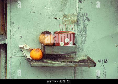 Vecchio bastoncini di incenso e di marcio arance al di fuori di una vecchia casa in Tai O villaggio di pescatori, Regione amministrativa speciale di Hong Kong Foto Stock