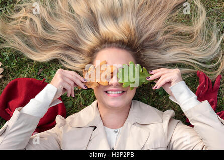 Donna sdraiata su un prato con gli occhi coperti con foglie Foto Stock