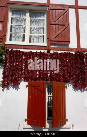 Peperoni rossi essiccazione su facciate di una tipica casa di Espelette. Paese basco. Pirenei Atlantiques.Francia. Foto Stock