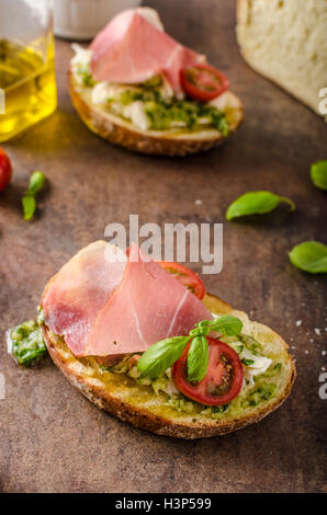 Tostare il pane toscano con pesto e prosciutto della Foresta Nera, delizioso pane fatto in casa e pesto, guarnita con parmigiano Foto Stock