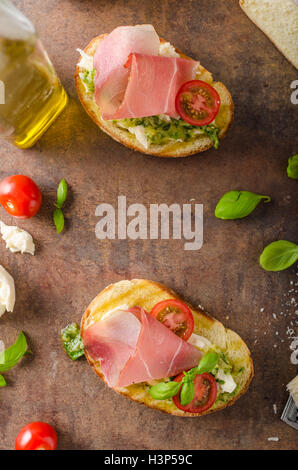 Tostare il pane toscano con pesto e prosciutto della Foresta Nera, delizioso pane fatto in casa e pesto, guarnita con parmigiano Foto Stock