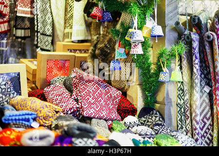 Stand con elementi ornamentali sciarpe, cappelli, calze, guanti e piccole decorazioni esposti per la vendita al mercato di Natale a Riga, Lettonia. Il mercato si svolge ogni anno nel mese di dicembre. Foto Stock