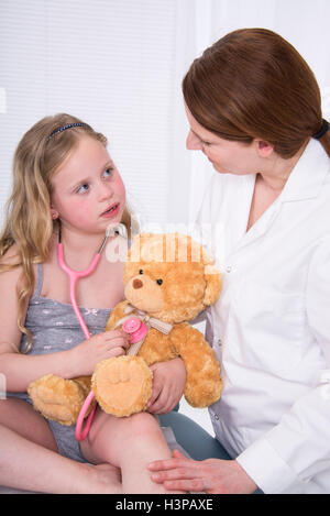 Modello rilasciato. Ragazza utilizzando uno stetoscopio con Teddy bear e infermiere. Foto Stock