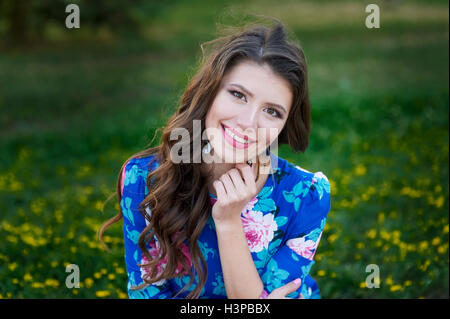 Ritratto di giovane donna riposo nel parco sorridente sull'erba Foto Stock