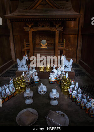 Lo Shintoismo santuario stradale offerte di inari tofu e kitsume fox guardian figure, un sacro specchio, Kawagoe Saitama, Giappone. Foto Stock