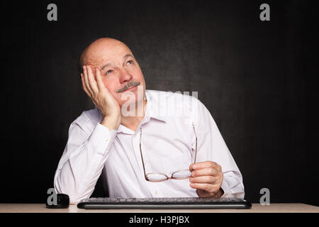 Uomo anziano che guarda lontano premurosamente, ponderando il problema o compito Foto Stock