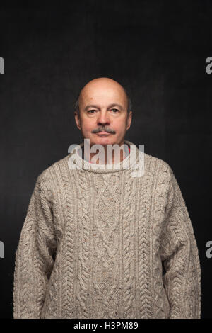 Ritratto di un uomo anziano con baffi in maglione a maglia. Guarda avanti. Foto Stock