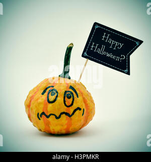 Primo piano di una zucca terrorizzata con una bandiera nera a forma di cartello con la questione happy Halloween? Scritto in essa, contro un o Foto Stock