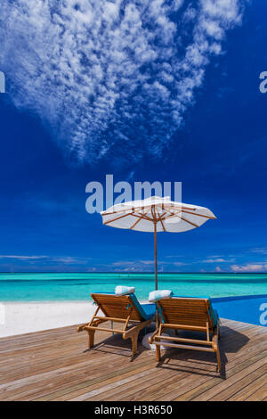 Ombrelloni e lettini in legno sulla spiaggia tropicale con la migliore vista sulla piscina Foto Stock