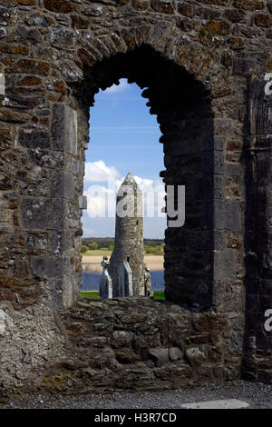 Clonmacnoise round tower attraverso la finestra insediamento monastico pietra intagliata monumento religioso di religione monastero Offaly RM Irlanda Foto Stock