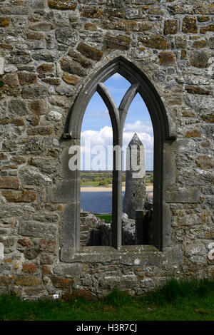 Clonmacnoise round tower attraverso la finestra insediamento monastico pietra intagliata monumento religioso di religione monastero Offaly RM Irlanda Foto Stock