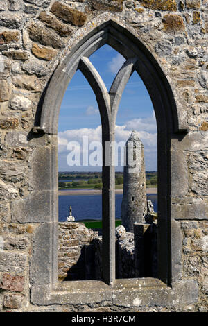 Clonmacnoise round tower attraverso la finestra insediamento monastico pietra intagliata monumento religioso di religione monastero Offaly RM Irlanda Foto Stock