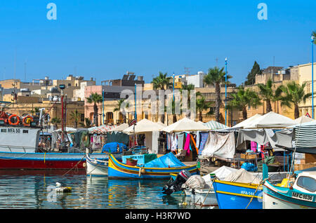 Tradizionali barche da pesca maltesi nel più grande villaggio di pescatori dell'isola, situato in corrispondenza della testa della Baia di Marsaxlokk - Marsaxlokk, Malta Foto Stock