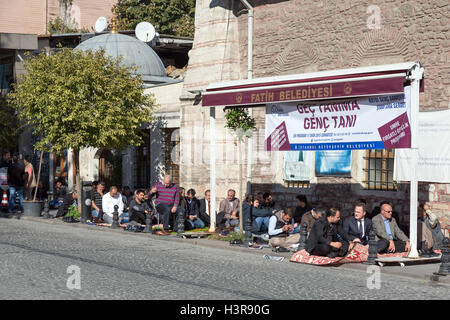 Moderno popolo turco seduto alla strada prima della cerimonia di preghiera Foto Stock