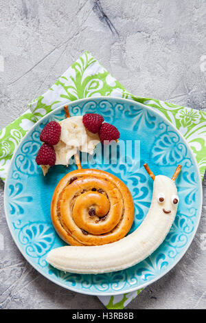 Fun food. La cannella bun con banana guardare come una lumaca Foto Stock