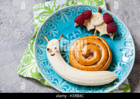 Fun food. La cannella bun con banana guardare come una lumaca Foto Stock