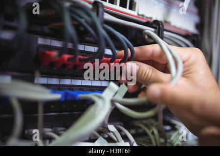 Il tecnico collegando il cavo patch in un rack server Foto Stock