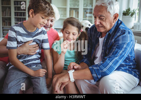 Nonni e nipoti guardando smartwatch in salotto Foto Stock