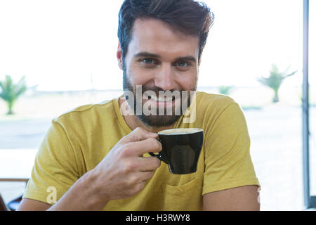 Uomo sorridente in possesso di una tazza di caffè Foto Stock