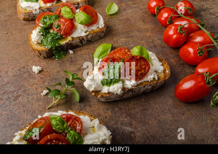 Tostato bruschetta con ricotta, pesto di basilico e pomodorini Foto Stock