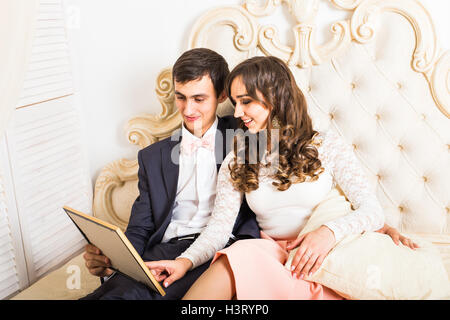 Giovane seduto sul letto guardando foto Foto Stock