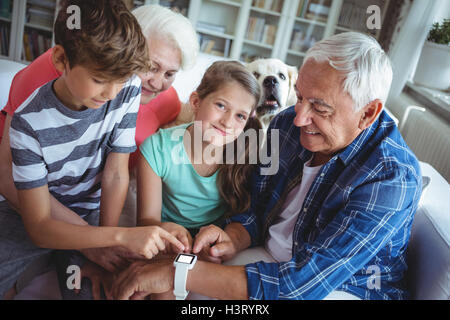 Nonni e nipoti guardando smartwatch in salotto Foto Stock