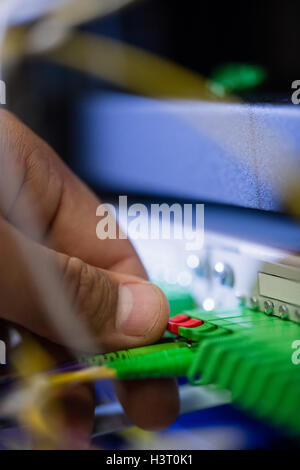 Il tecnico collegando il cavo patch in un rack server Foto Stock