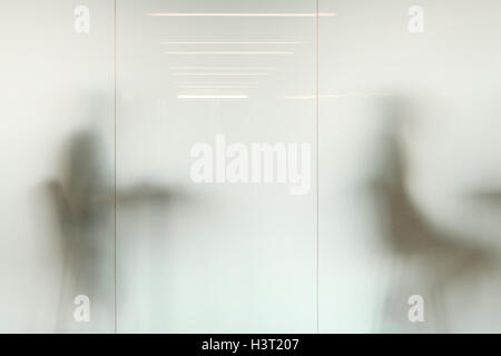 Sfocato figure sedute dietro divisori in vetro smerigliato Foto Stock