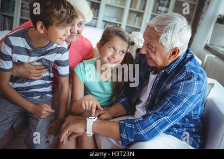 Nonni e nipoti guardando smartwatch in salotto Foto Stock